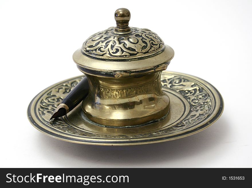 A gold plated antique inkpot and pen on white background. A gold plated antique inkpot and pen on white background.