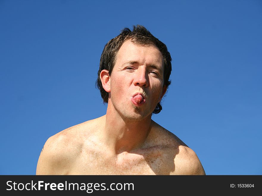Man pulling tongue on a blue sky