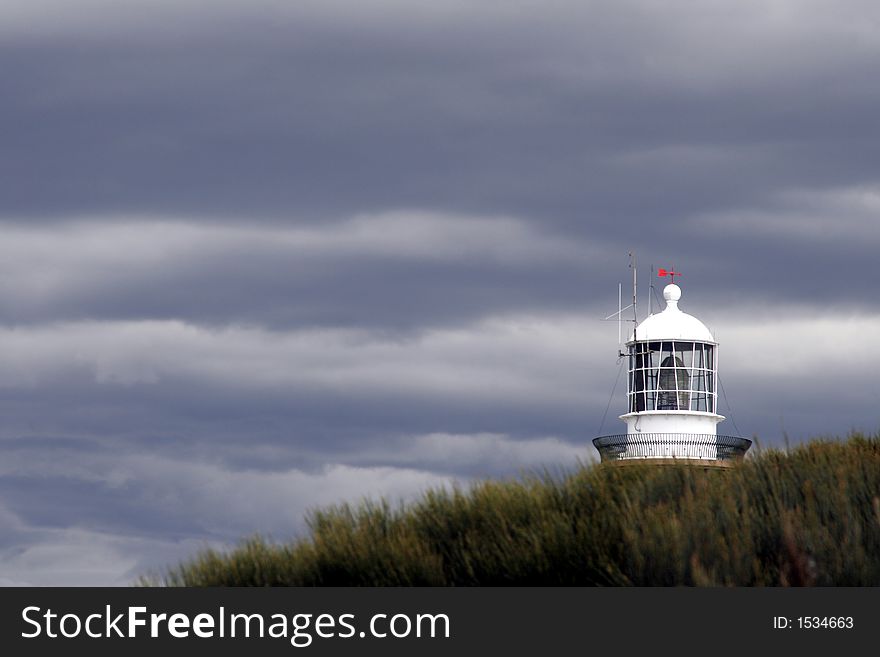 Lighthouse Top Behind A Hill On A Stormy Cloudy Day