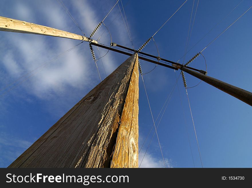 View of power lines from below with blue sky and clouds