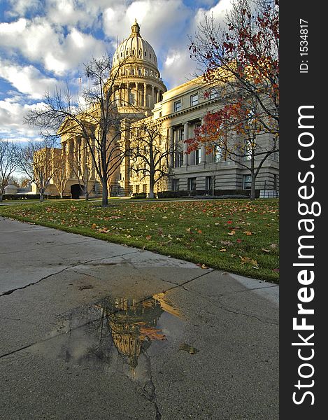 Capital building reflecting in a puddle with dramatic clouds