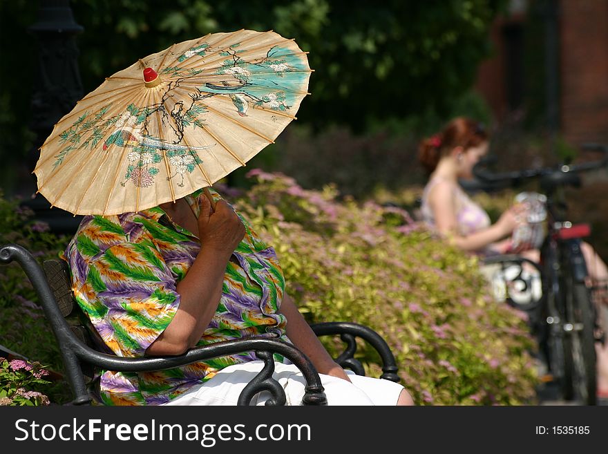 Old woman in Hawaiian shirt with Chinese umbrella. Old woman in Hawaiian shirt with Chinese umbrella