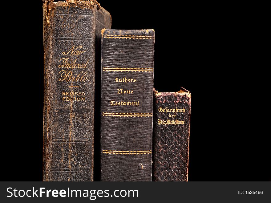 Three very old bibles including two German bibles standing on a table awash in warm light