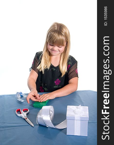 Young girl wrapping green gift at table for christmas. Young girl wrapping green gift at table for christmas