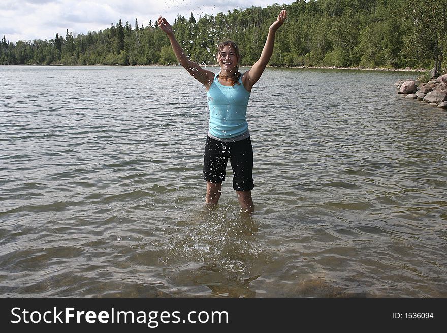 Teen splashing water in the air at the lake. Teen splashing water in the air at the lake.