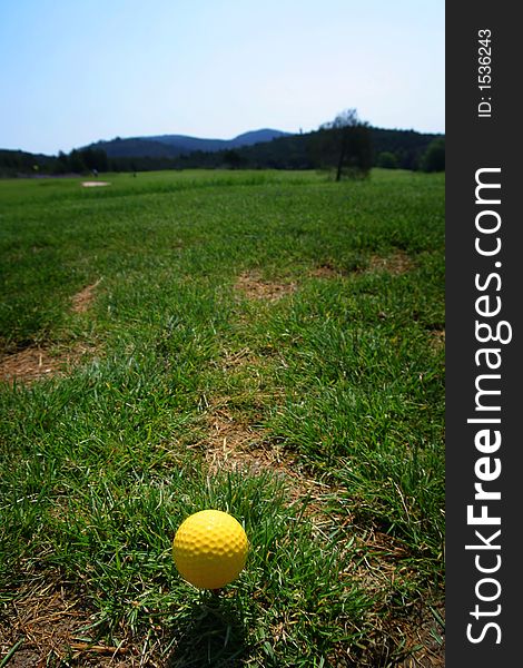 Yellow golf ball standing on green grass, wide angle photo. Yellow golf ball standing on green grass, wide angle photo