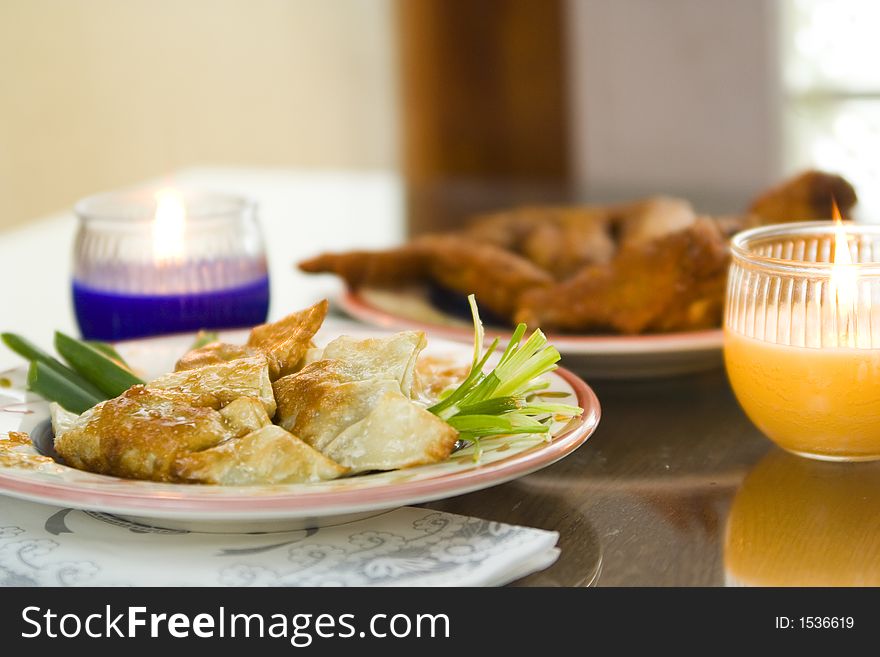 Chinese pan fried dumpling and chinese fried chicken wings on the table with 2 candles. Chinese pan fried dumpling and chinese fried chicken wings on the table with 2 candles