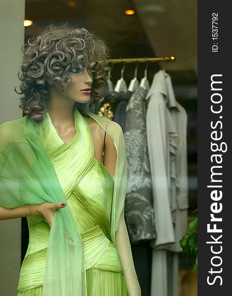 Doll in a green dress in a show-window of shop. Doll in a green dress in a show-window of shop