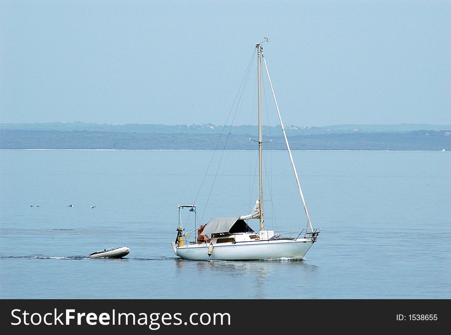 Sail boat and small rescue boat at the open sea