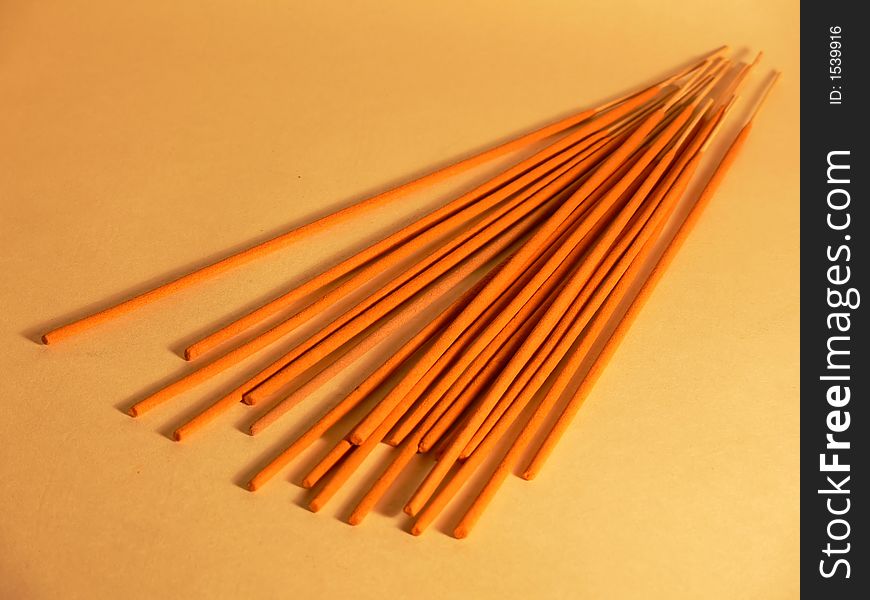 Orange incense sticks on yellow background