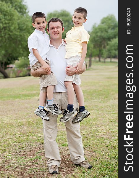 Father carrying his two sons in his hands on a natural background. Father carrying his two sons in his hands on a natural background