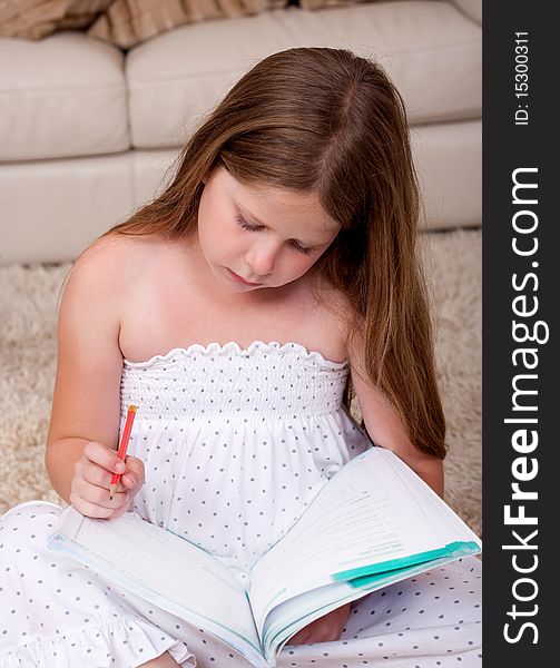Young school girl sitting and reading book in living room. Young school girl sitting and reading book in living room