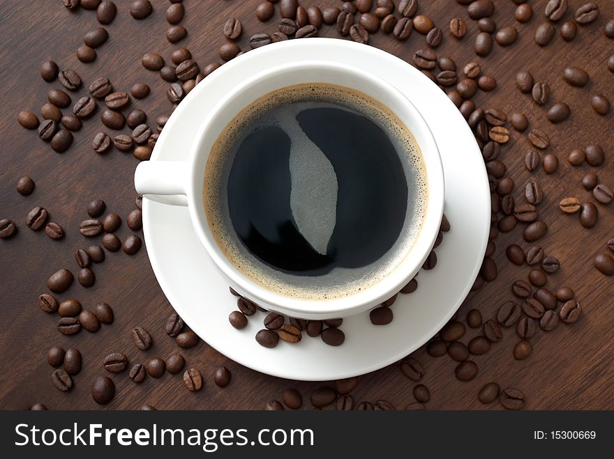 A cup of hot coffee on the table with coffee beans