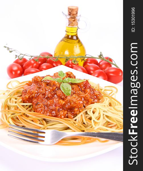 Colorful spaghetti bolognese on a plate, some fresh tomatoes and olive oil