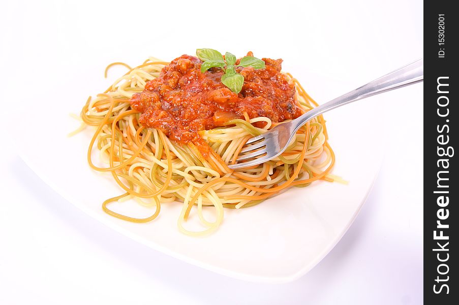 Colorful spaghetti bolognese on a plate being eaten with a fork