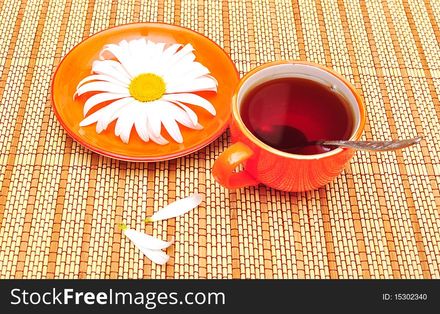 Orange cup tea  and camomiles at the background