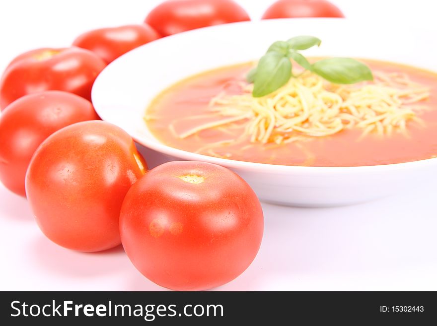 Tomato soup with macaroni decorated with basil with fresh tomatoes around it