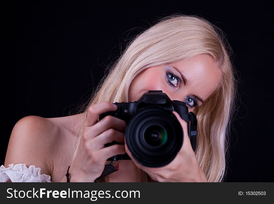 Blonde hair woman, holding camera aimed in front of you. Black Background. Blonde hair woman, holding camera aimed in front of you. Black Background.