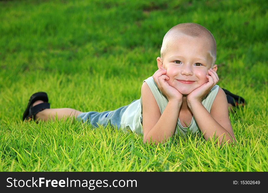 Cheerful child lying on green grass and smiling. Cheerful child lying on green grass and smiling