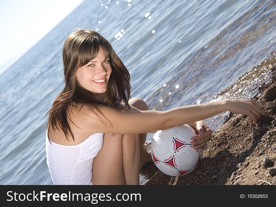 Beautiful young girl in white with a ball on sunny beach. Beautiful young girl in white with a ball on sunny beach