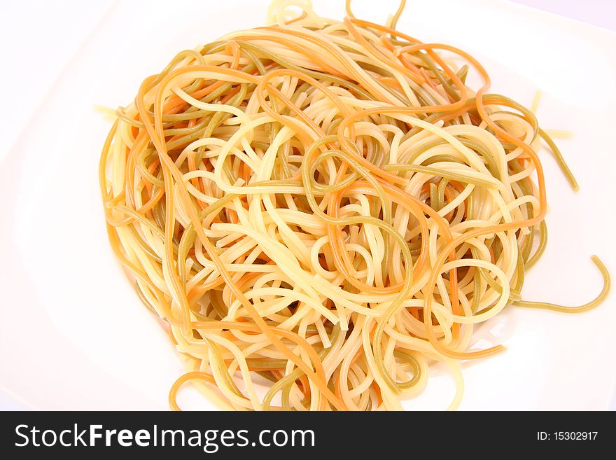 Tricolor cooked spaghetti on a plate in close up
