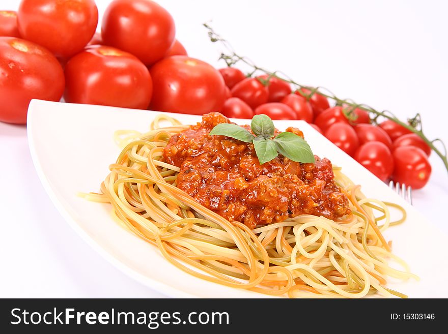 Colorful spaghetti bolognese on a plate and some fresh tomatoes