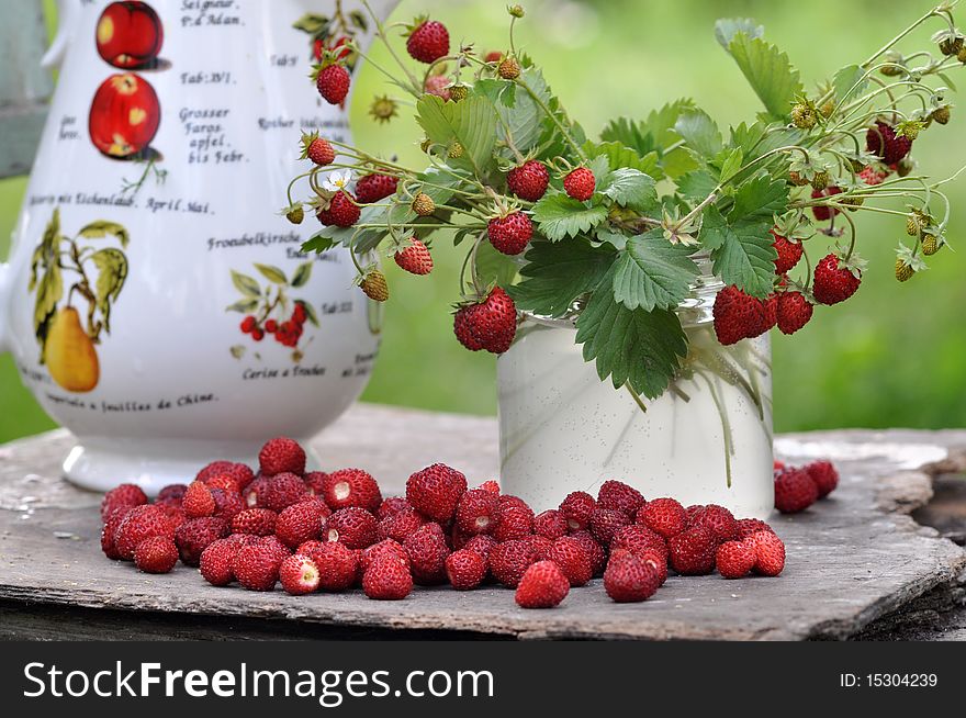 Sprigs with a strawberry stand in a glass jar, the mineral deposit of strawberry lies alongside