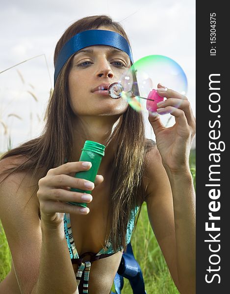 Beauty young woman blowing soap bubbles in summer day. Beauty young woman blowing soap bubbles in summer day