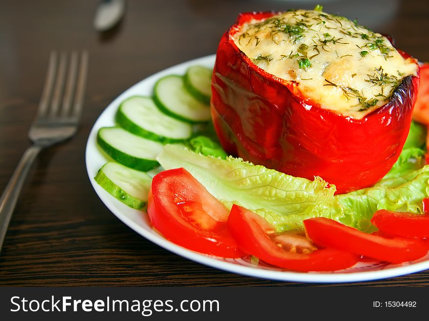 Close-up baked red paprika filling with eggs and cheese, served with fresh vegetables. Close-up baked red paprika filling with eggs and cheese, served with fresh vegetables