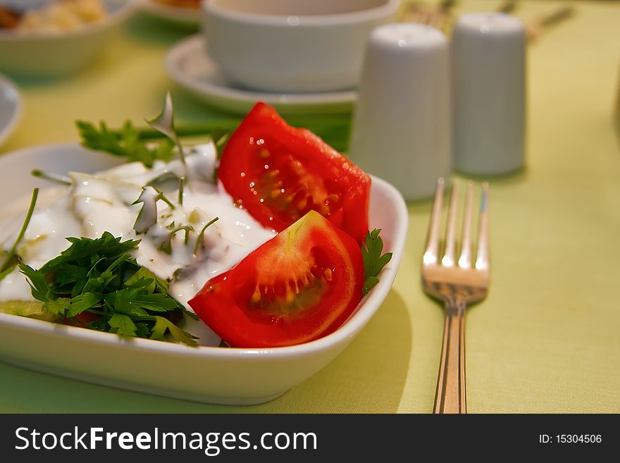 Close-up healthy appetizer for dinner - fresh salad with tomatoes, greenery and yoghurt. Close-up healthy appetizer for dinner - fresh salad with tomatoes, greenery and yoghurt