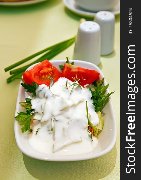 Close-up healthy appetizer for dinner - fresh salad with tomatoes, greenery and yoghurt. Close-up healthy appetizer for dinner - fresh salad with tomatoes, greenery and yoghurt