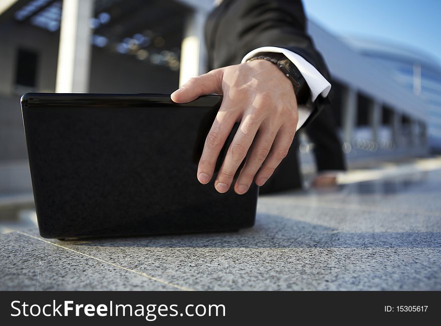 Businessman closing a laptop on the street