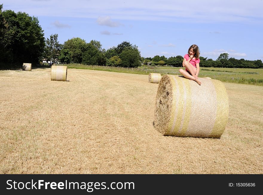 White teenager standing on hay bales in summer season, trees and blue sky in background from Wrest UK. White teenager standing on hay bales in summer season, trees and blue sky in background from Wrest UK