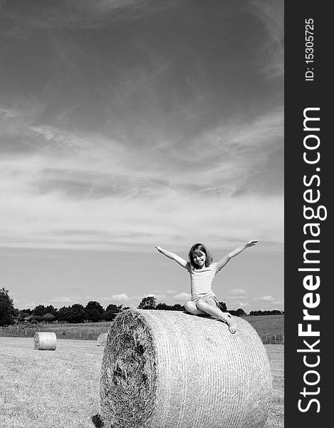 White girl having fun on hay bales in summer season, blue sky in background. White girl having fun on hay bales in summer season, blue sky in background