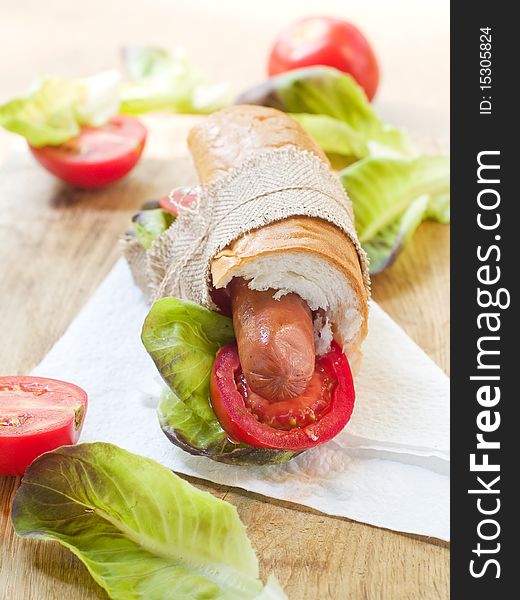 Sausages in baguette with fresh tomato and lettuce. Sausages in baguette with fresh tomato and lettuce