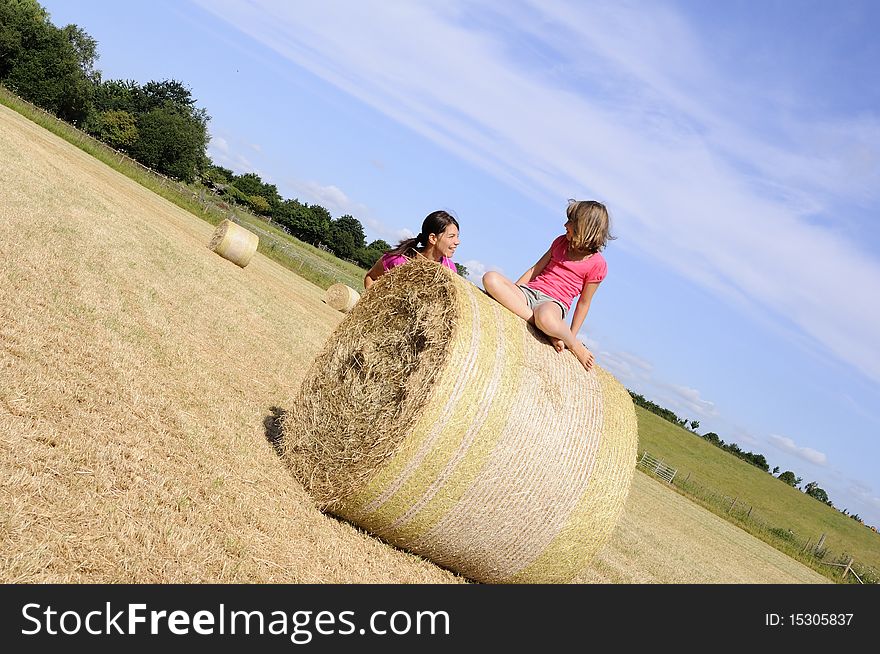 White girls playing with hay bales in summer season, blue sky in background. White girls playing with hay bales in summer season, blue sky in background