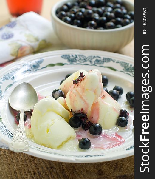 Lemon sorbet with black currant and bowl of black currant on background