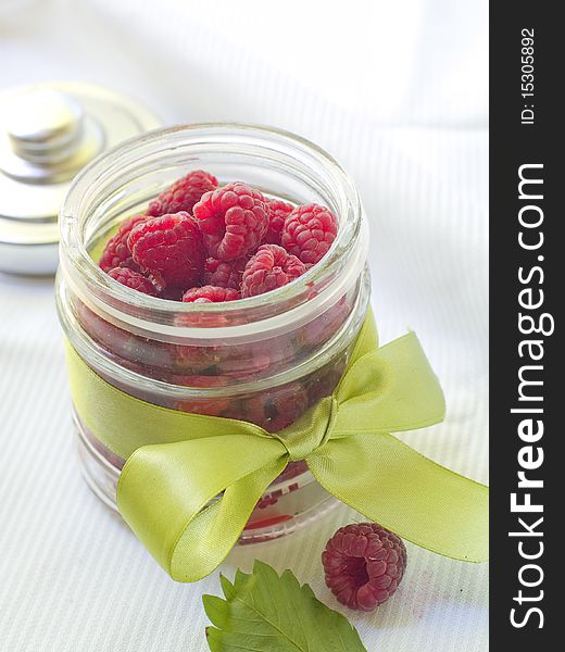 Fresh raspberries in jar with bow