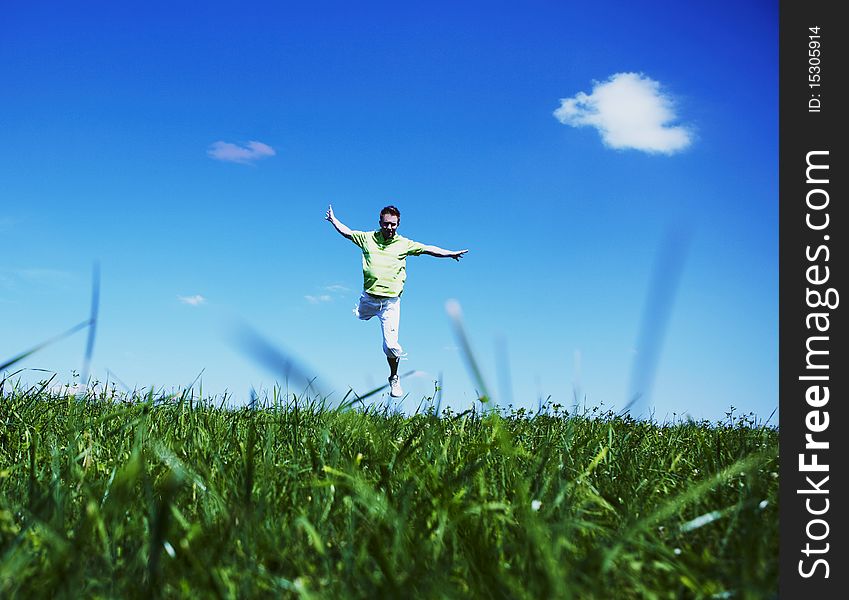 Jumping up guy in a green shirt against blue sky. photo