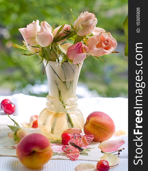 Roses in vase with butterfly and fresh apricot on foreground