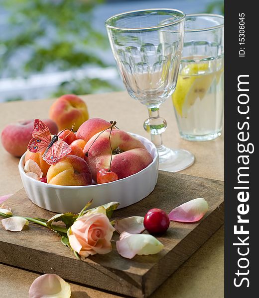 Fresh apricots, plums, cherry in bowl with butterfly rose on foreground. Fresh apricots, plums, cherry in bowl with butterfly rose on foreground