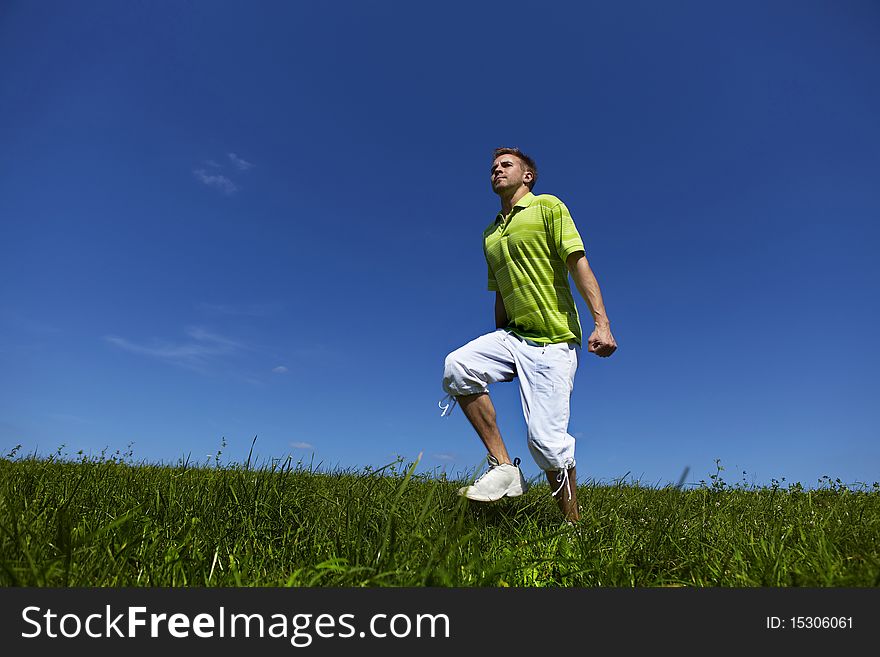 Jumping Up Guy In A Green Shirt Against Blue Sky.