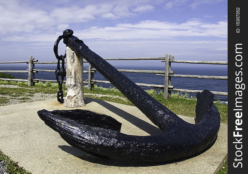 Old black anchor on display in front of the ocean