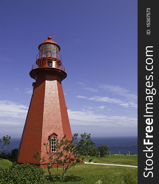 Old wooden red lighthouse standing in front of the ocean