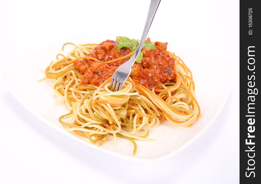 Colorful spaghetti bolognese on a plate being eaten with a fork