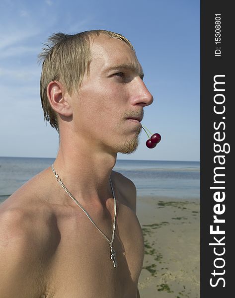 Young man with two cherry in the mouth. Young man with two cherry in the mouth.