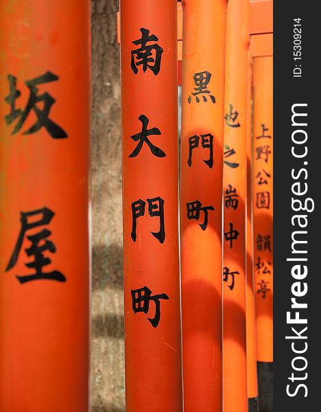 Japanese script on the bright orange arches leading to a temple.
