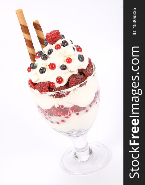 Whipped cream with raspberries, red currants and blue berries in a glass cup, decorated with a wafer tube. Whipped cream with raspberries, red currants and blue berries in a glass cup, decorated with a wafer tube