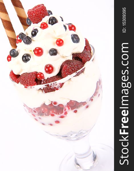 Whipped cream with raspberries, red currants and blue berries in a glass cup, decorated with a wafer tube. Whipped cream with raspberries, red currants and blue berries in a glass cup, decorated with a wafer tube