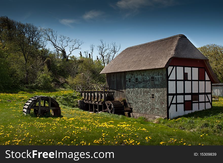 Vintage danish water mill captured on a sunny day with blue sky and flowers in the foreground. Vintage danish water mill captured on a sunny day with blue sky and flowers in the foreground.